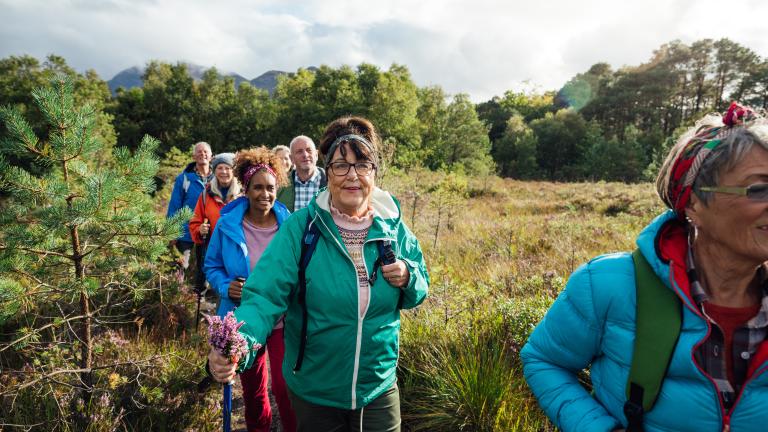 People walking in a line in the countryside, wearing walking gear