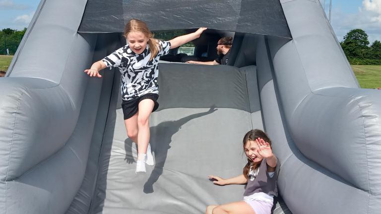 Two children laughing on an inflatable grey slide