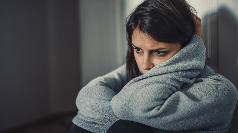A solemn woman wraps her arms around her head