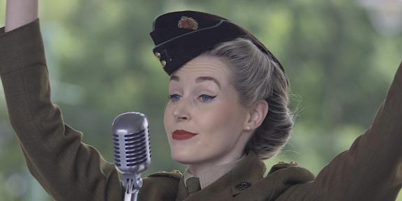 A female singer in clothes from the era behind a microphone