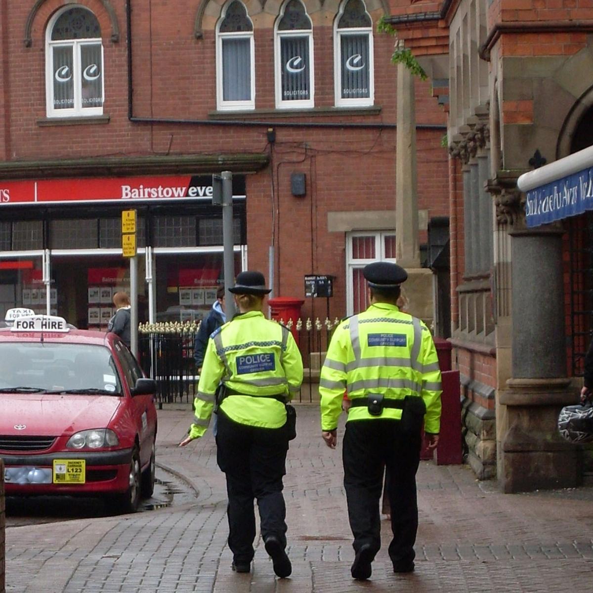 Two police officers walk down a street