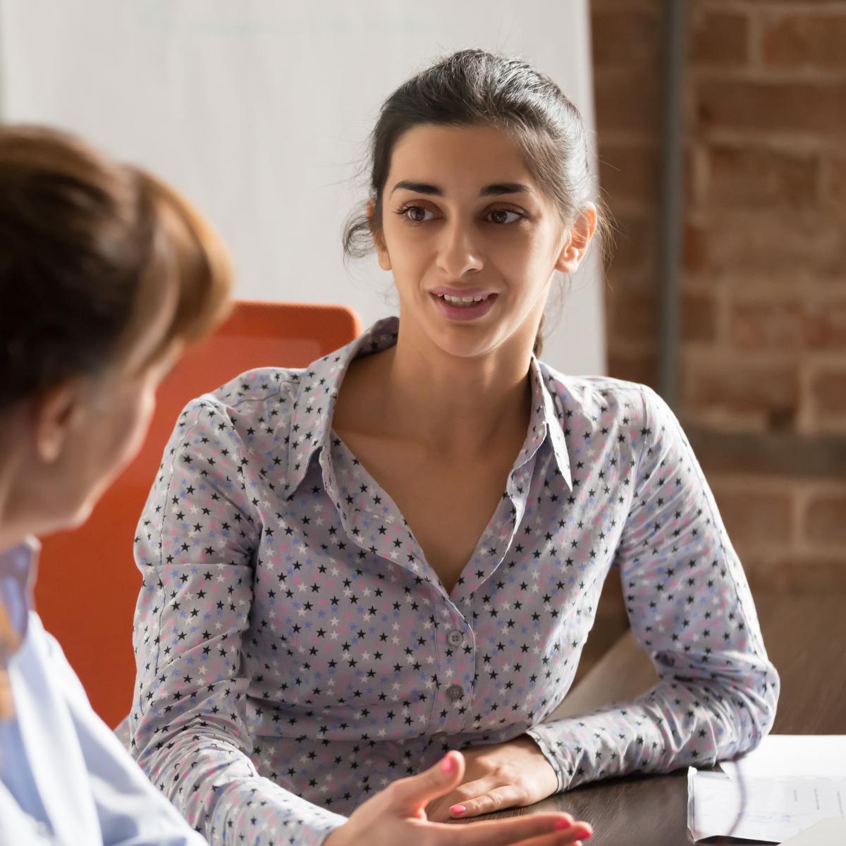 Two women sit and talk