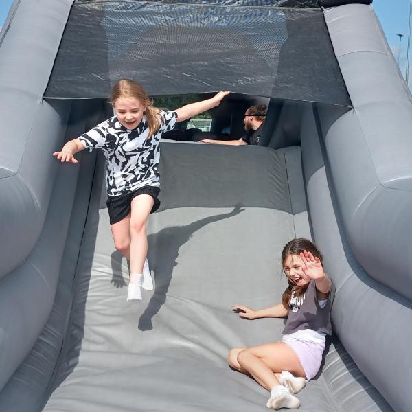 Two children laughing on an inflatable grey slide