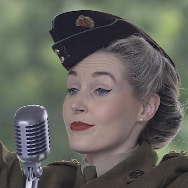 A female singer in clothes from the era behind a microphone